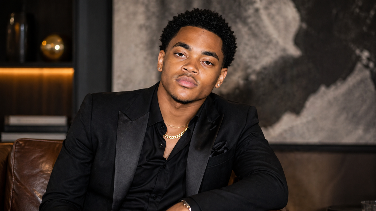 Young man in a black suit posing in a modern indoor studio portrait related to Michael Rainey Jr net worth with a stylish and confident look